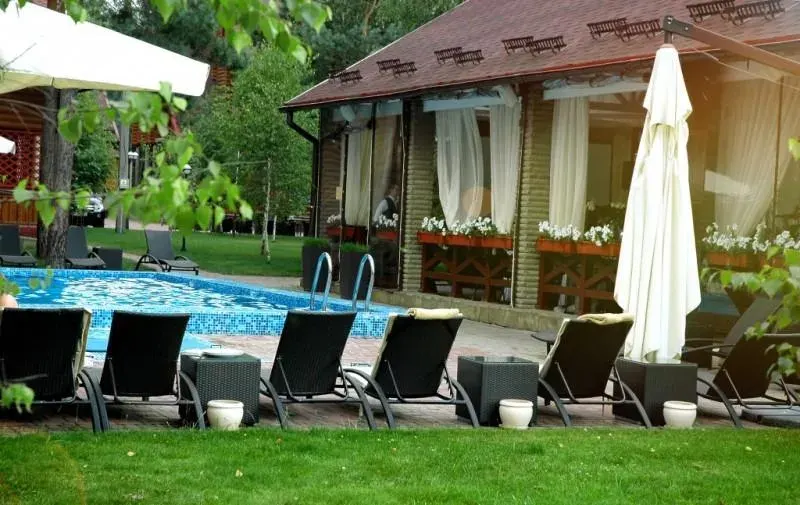 Шезлонги й білі парасолі біля літнього басейну